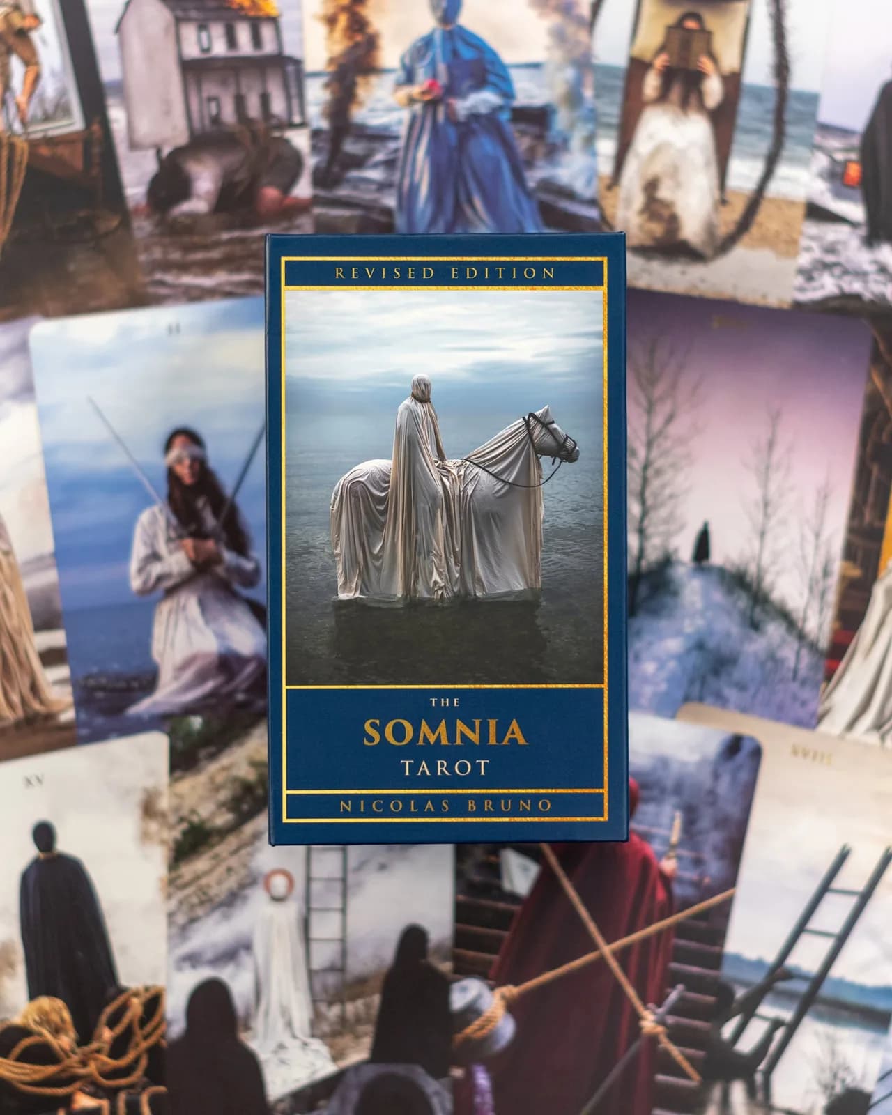 The Somnia Tarot revised edition box showing a cloaked figure beside a white horse in shallow water, resting on scattered cards
