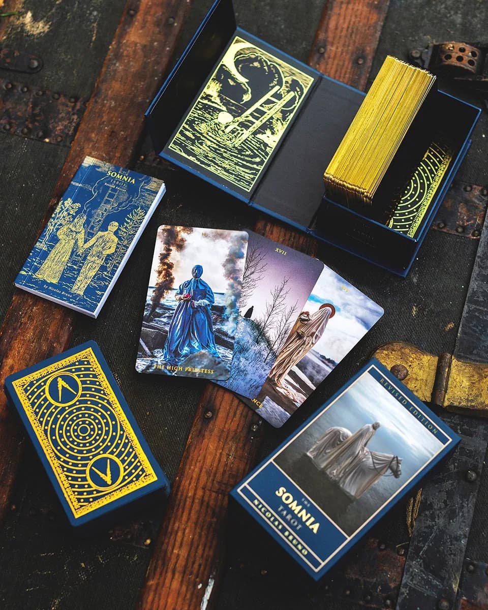 Overhead flat lay of the gold moon and compass card back, deck box and art booklet with The High Priestess card visible