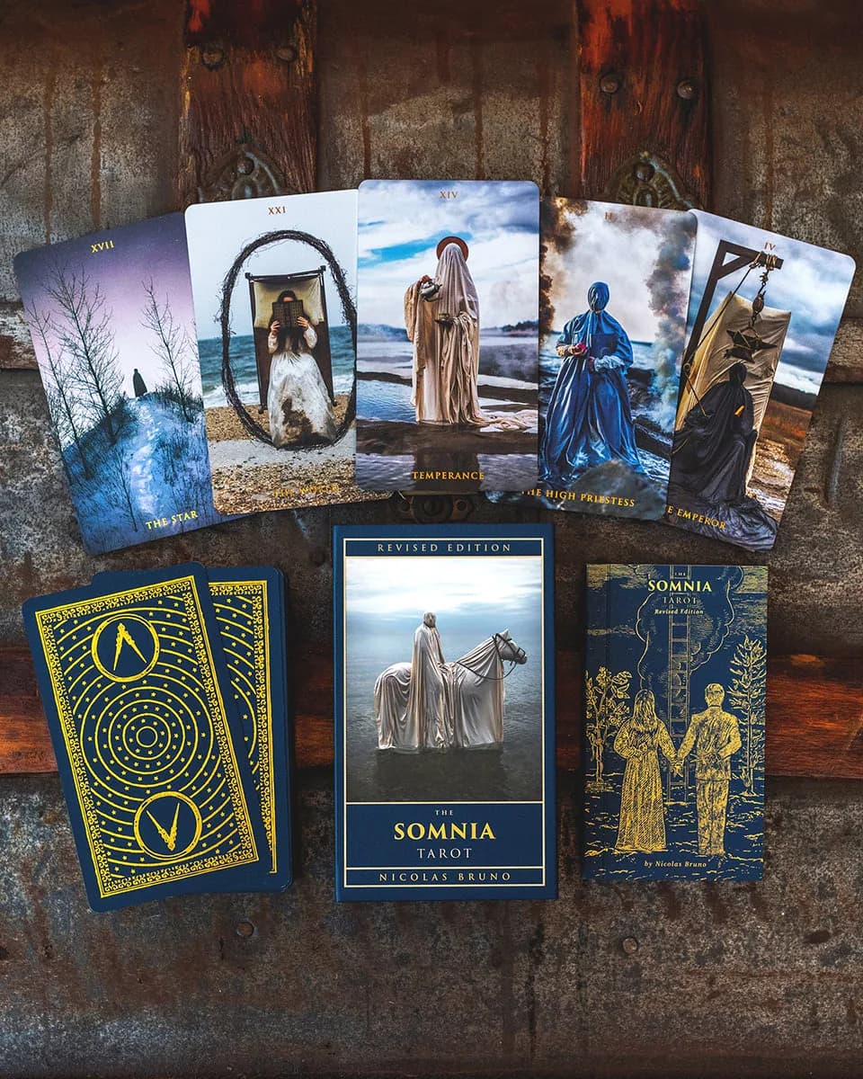 Five fanned Somnia Tarot cards including The Star and Temperance above the stacked deck and box on weathered wood