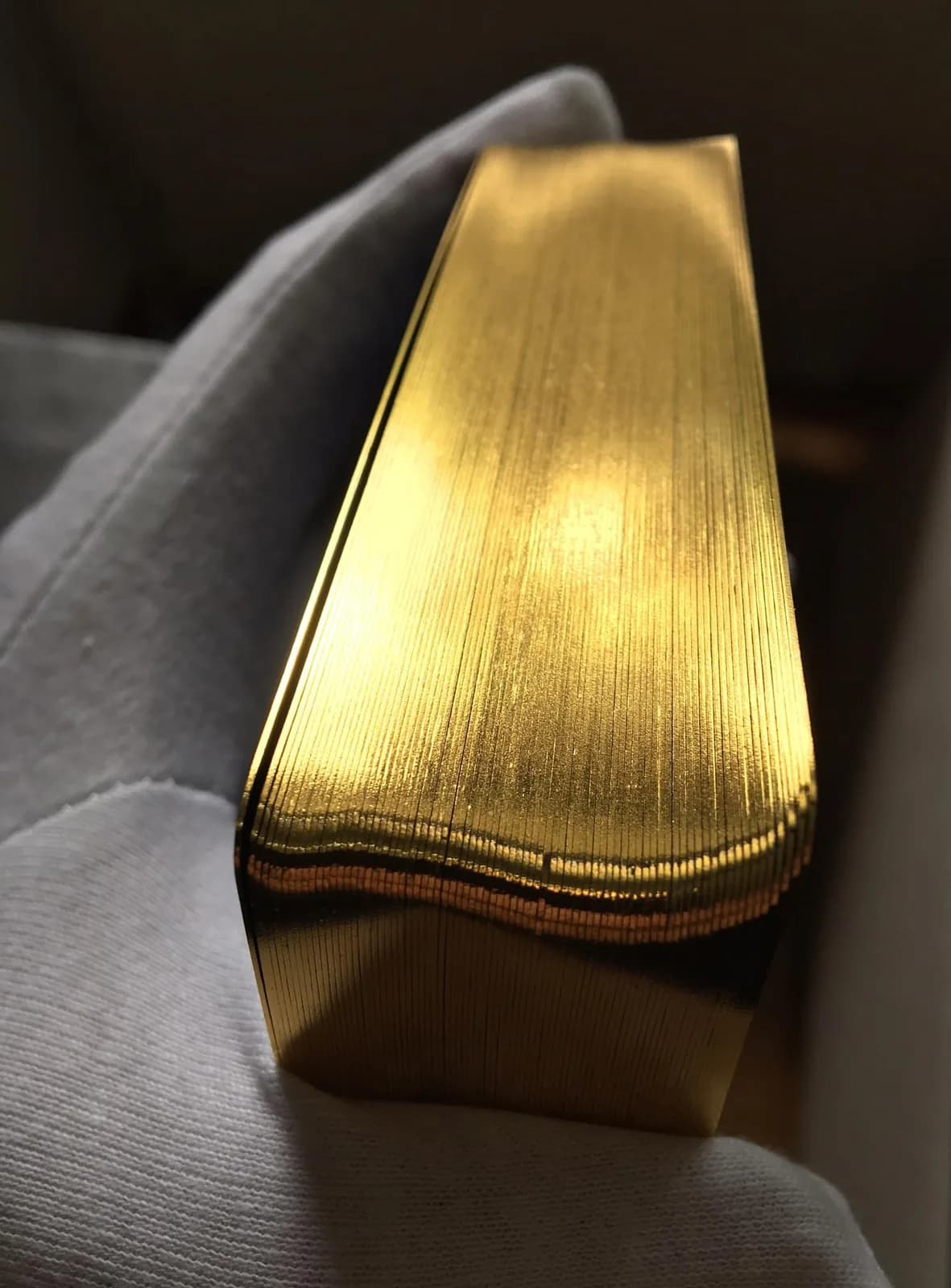 Close up of the gold gilded edges of the Time Tarot deck resting on grey fabric
